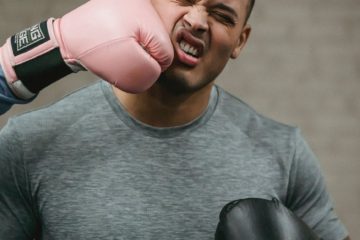 unrecognizable boxer hitting young ethnic sportsman during training